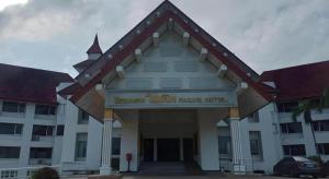 um grande edifício branco com uma placa na frente em Pailyn Hotel em Sukhothai