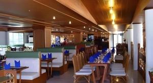 um restaurante com mesas e cadeiras com guardanapos azuis em Pailyn Hotel em Sukhothai