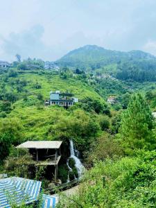 a house on top of a hill with a waterfall at River Side Gorilla Resort Mussoorie in Mussoorie