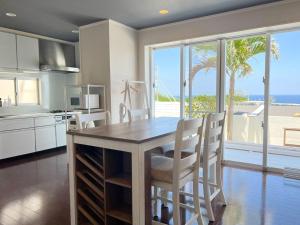 a kitchen with a table and chairs with a view of the ocean at 全室オーシャンビュー外階段付き一棟貸切プライベートヴィラ in Kouri