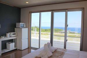 a bedroom with a bed with a view of the ocean at 全室オーシャンビュー外階段付き一棟貸切プライベートヴィラ in Kouri