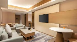 ein Wohnzimmer mit einem weißen Sofa und einem Fernseher in der Unterkunft Zhangjiagang Guomao Hotel in Zhangjiagang