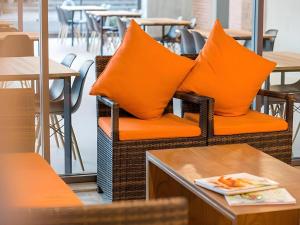 乌隆他尼B2 Udon Thani Boutique and Budget Hotel的餐厅内藤椅上的两个橙色枕头