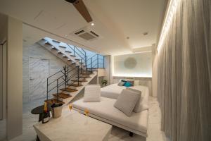 Una sala de estar con un sofá blanco y una escalera. en THE ZK West Coast, en Awaji