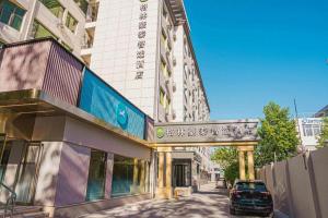 um carro está estacionado em frente a um edifício em GreenTree Inn Beijing Capital Airport New International Exhibition Center Express Hotel em Pequim