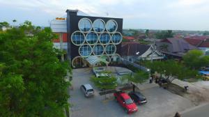 a building with cars parked in a parking lot at Fovere Hotel Palangkaraya in Palangkaraya