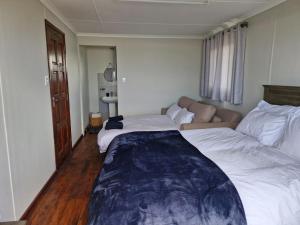 a hotel room with two beds and a couch at Casa 14 Zimilene Xai Xai in Xai-Xai