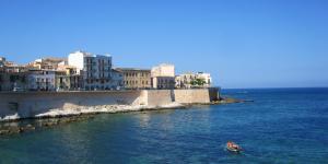 a small boat in the water next to a city at Syrakosia a Ortigia in Syracuse