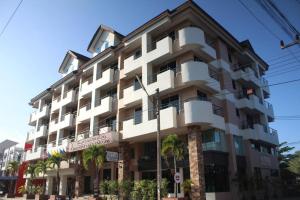 a large white building with palm trees in front of it at Butterfly Princess Hotel in Ban Komo Sip Paet