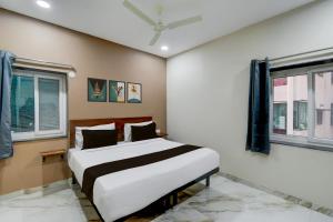 una cama en una habitación con dos ventanas en Hotel O PRIME HUB, en Lingampalli