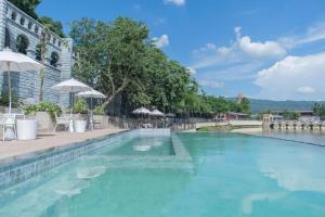 einen Pool mit blauem Wasser und Sonnenschirmen in der Unterkunft Verona Boutique Hotel - The Verona Co., Ltd in Ban Wang Khon Daeng