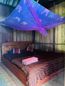 Un dormitorio con una cama con dosel morado. en Tina's Homestay-Tadlo, en Tad Lo