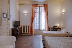 een hotelkamer met 2 bedden en een televisie bij Hôtel des Facultés in Lyon