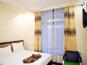 una camera con letto, sedia e tende di Best Point Hotel a Dar es Salaam