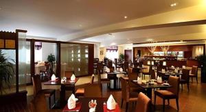 a restaurant with tables and chairs and a bar at Grand Mercure Teda Dalian in Dalian