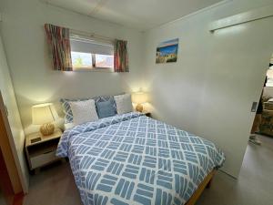 una camera con un letto blu e bianco e una finestra di Cosy Corner Cabin a Broadwater Altre 26 foto