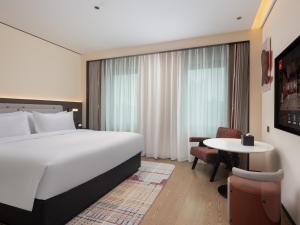 ein Hotelzimmer mit einem großen Bett und einem Tisch in der Unterkunft Radisson Blu Hotel Wuhan Jianghan Road Pedestrian Street in Wuhan