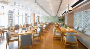 um restaurante com mesas e cadeiras de madeira e janelas em Warmly Hotel Suzhou Shuanghuwan em Suzhou