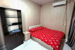 a bedroom with a bed with a red comforter at Apartment for 5 persons, in Chilanzar in Tashkent +3 photos