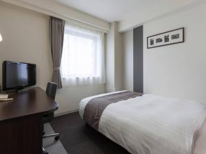 ein Hotelzimmer mit Bett, Schreibtisch und Fernseher in der Unterkunft Comfort Hotel Akita in Akita