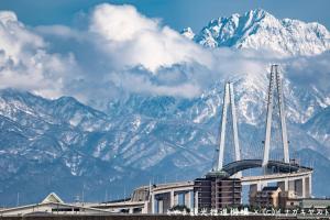 a building in front of a snow covered mountain at Comfort Hotel Toyama in Toyama