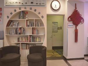 une chambre avec deux chaises et une étagère avec des livres dans l'établissement Shell Baoding Dongfeng Middle Road Kailian Hotel, à Baoding
