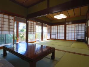 una habitación con una mesa de madera en una habitación con ventanas en 眺望の湯宿弁天, en Tonami
