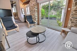 een woonkamer met een tafel, stoelen en een televisie bij Ti coz in Lézardrieux +16 foto's