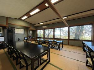 Una sala de conferencias con mesas, sillas y ventanas. en 眺望の湯宿弁天, en Tonami