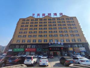 un grand bâtiment avec des voitures garées devant dans l'établissement 7 Days Inn Yining Xintiandi, à Yining