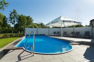 einen Pool mit Sonnenschirm neben einer Terrasse in der Unterkunft Landhotel Huberhof in Allershausen