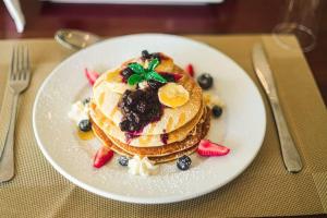 a white plate with pancakes and berries on a table at Pemabwe Guest Lodge in Harare