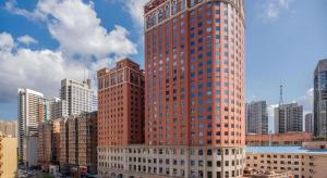 a tall red building in a city with buildings at Dalian Liangyun Hotel in Dalian