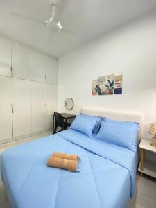 una camera con un letto blu e un asciugamano sopra di Youth City 2 Bedroom Suites with Rooftop Pool Nilai by D'KAY HOMES, near USIM KLIA a Nilai