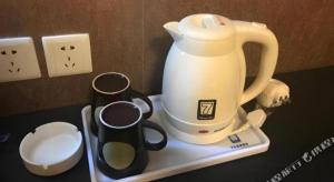 a tea kettle and measuring cups on a tray at 7 Days Inn Qingdao Liaoyang West Road Xinye Plaza Metro Station in Qingdao
