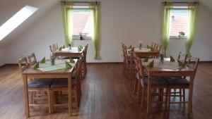a dining room with wooden tables and chairs and windows at Wellness Pension Salzgrotte in Sondernau