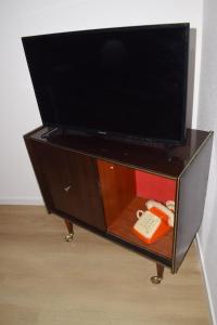 - une télévision au-dessus d'une armoire avec télécommande dans l'établissement Le 70s 2 pièces proche Colmar, à Holtzwihr