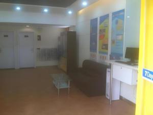 a room with a couch and a desk and a table at 7 Days Inn Qingdao Shandong Road Zhenning Overpass Branch in Qingdao