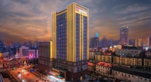 济南Echarm Hotel Jinan Railway Station Daming Lake的夜晚城市里灯火通明的建筑