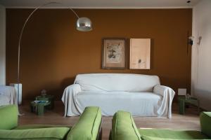 a living room with a white couch and green chairs at Cottage di design con giardino in Bosco Marengo