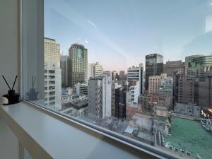 een raam met uitzicht op de skyline van de stad bij The Comfort in Seoul