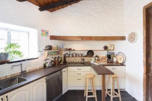 a kitchen with a sink and a counter with stools at Sansofi Guesthouse in San Miguel de Abona