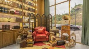 a library with a red chair and books and a window at James Joyce Coffetel·Suqian Bus Station in Suqian