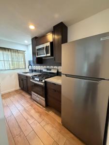 a kitchen with a stainless steel refrigerator and wooden floors at Mission Bell Motel in Ventura