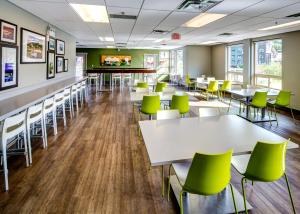 a cafeteria with white tables and green chairs at HI Whistler - Hostel in Whistler
