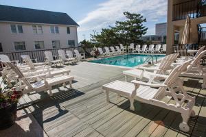 um grupo de cadeiras brancas e uma piscina em Beach View Hotel em Rehoboth Beach