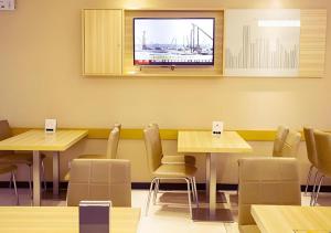 ein Restaurant mit Tischen und Stühlen und einem Fernseher an der Wand in der Unterkunft City Comfort Inn Huangshi City Huangshi Avenue in Huangshi