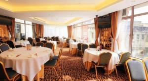 um restaurante com mesas, cadeiras e janelas brancas em Towns Well Motel em Macau