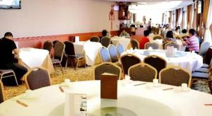 um grupo de pessoas sentadas em mesas em uma sala em Towns Well Motel em Macau