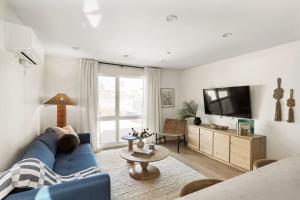 Una sala de estar con un sofá azul y un televisor en Tide House - Unit A - Modern Seaside 1BD w Parking, en El Segundo
